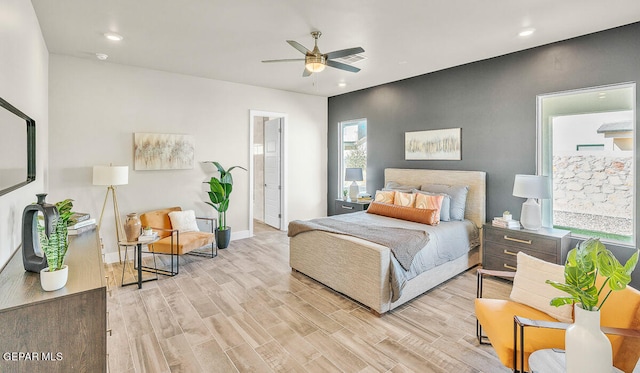 bedroom with ceiling fan, ensuite bathroom, and light wood-type flooring