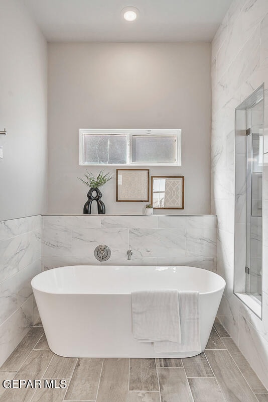 bathroom featuring a tub, tile flooring, and tile walls