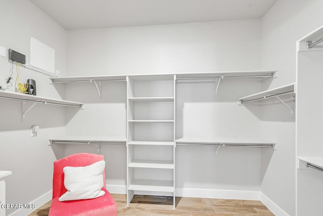 walk in closet with light hardwood / wood-style floors