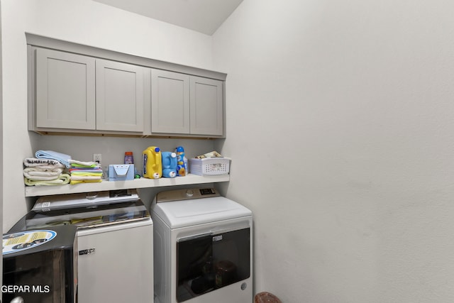 laundry room featuring washer and clothes dryer and cabinets