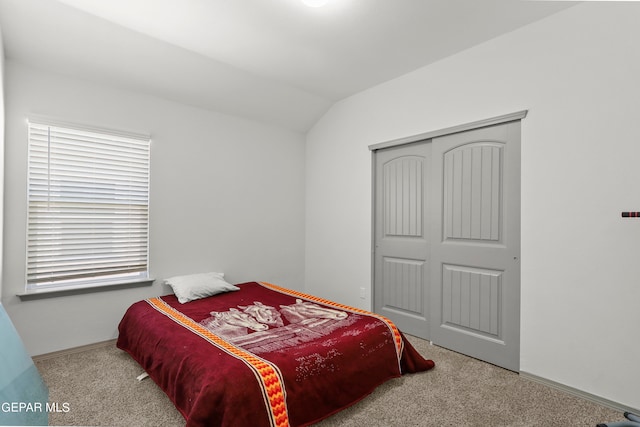 bedroom with light colored carpet, a closet, and lofted ceiling