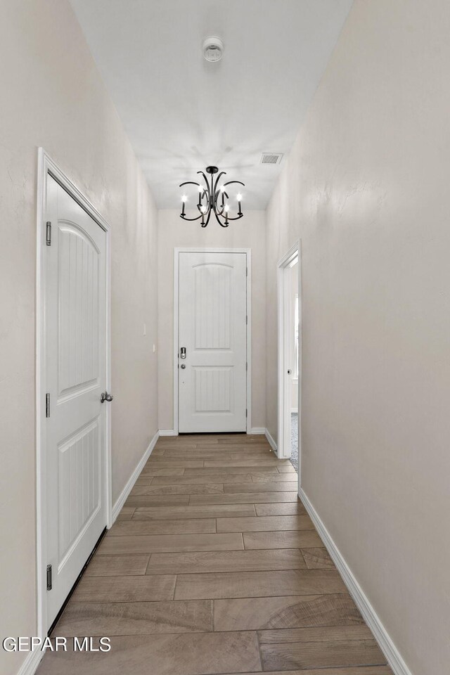 hall featuring light hardwood / wood-style floors and an inviting chandelier