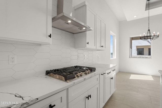 kitchen featuring white cabinetry, light stone counters, wall chimney exhaust hood, pendant lighting, and stainless steel gas stovetop