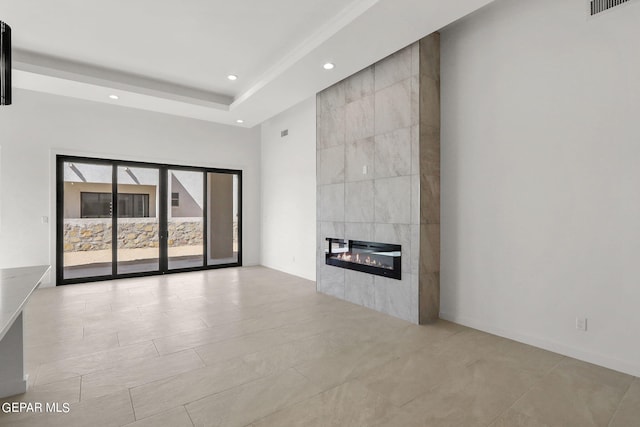 unfurnished living room featuring a tray ceiling and a tile fireplace