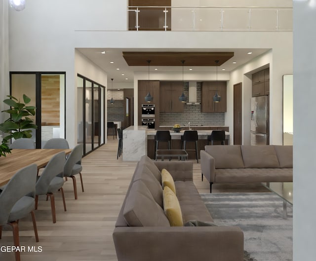 living area with recessed lighting, light wood-style flooring, and a towering ceiling