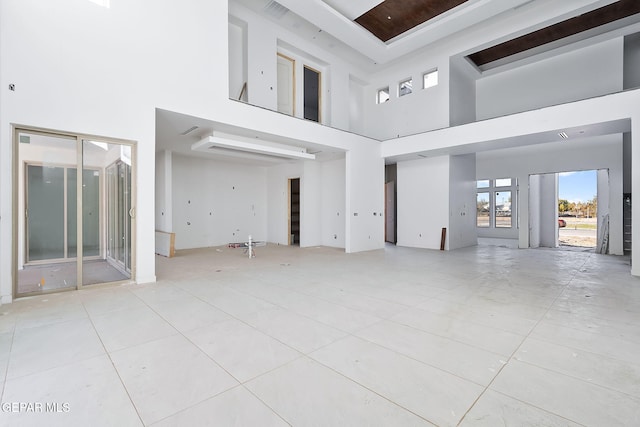 unfurnished living room with light tile patterned floors and a towering ceiling