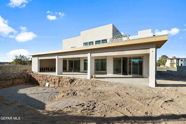 rear view of house with a patio, a balcony, and stucco siding