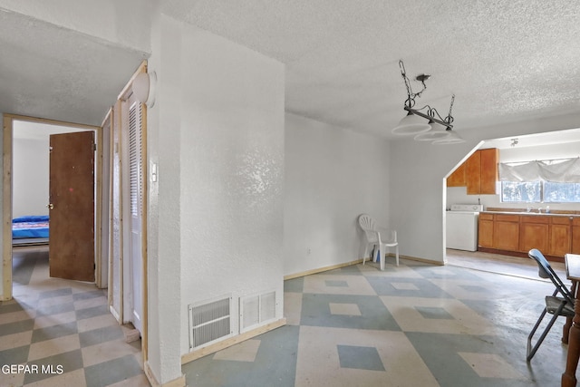 interior space featuring sink, a textured ceiling, and washer / clothes dryer