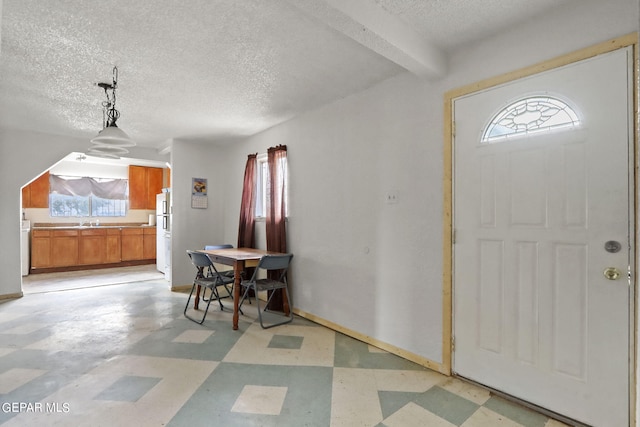 tiled entryway with a healthy amount of sunlight, sink, beam ceiling, and a textured ceiling