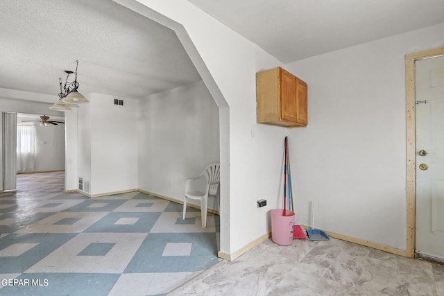 interior space with ceiling fan, a textured ceiling, and light tile flooring