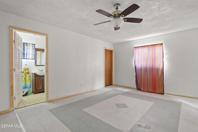 tiled spare room with sink, ceiling fan, and a textured ceiling