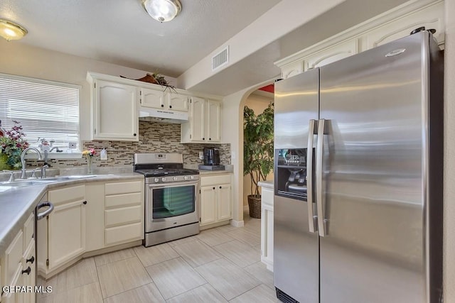 kitchen featuring white cabinets, sink, tasteful backsplash, light tile patterned flooring, and stainless steel appliances