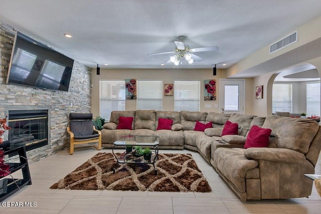 living room with ceiling fan and a fireplace