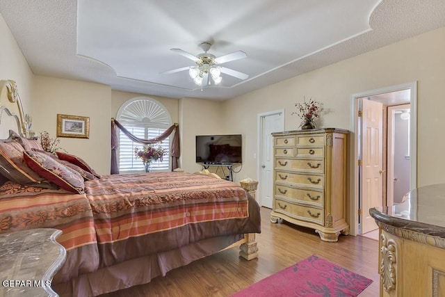 bedroom with a textured ceiling, light wood-type flooring, and ceiling fan