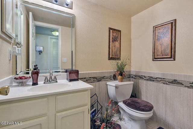 bathroom with vanity, toilet, and tile walls