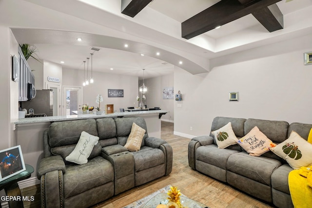 living room featuring beam ceiling, light hardwood / wood-style floors, and a notable chandelier