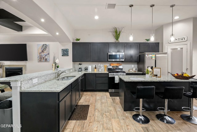 kitchen with kitchen peninsula, appliances with stainless steel finishes, a breakfast bar area, and sink