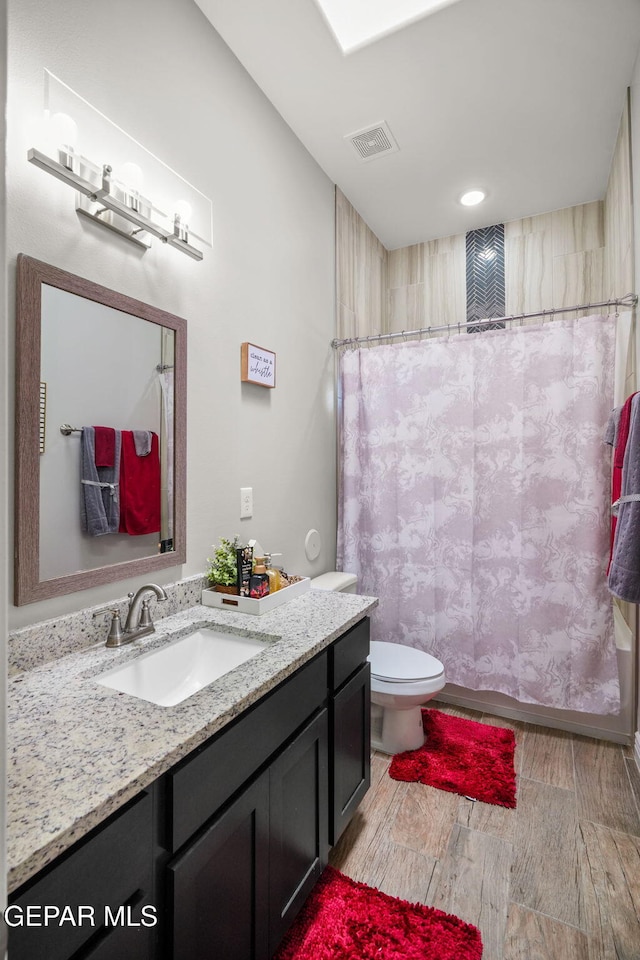 bathroom featuring a shower with shower curtain, vanity, and toilet