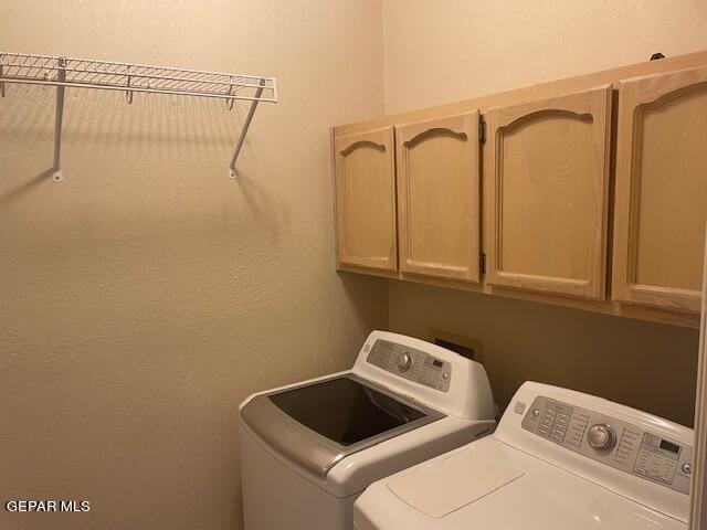 laundry room featuring washing machine and clothes dryer and cabinets