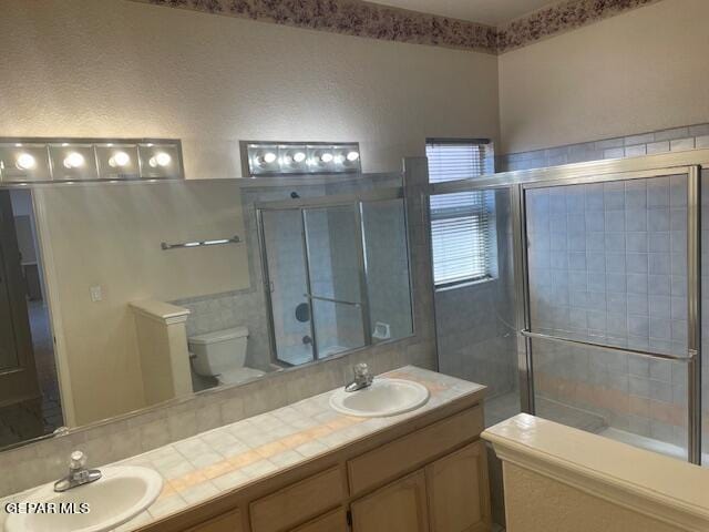 bathroom featuring vanity, toilet, and a shower with shower door