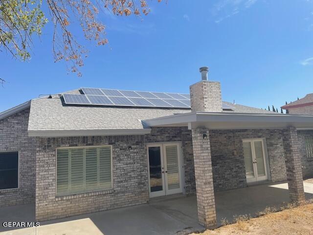 back of house with french doors, a patio, and solar panels