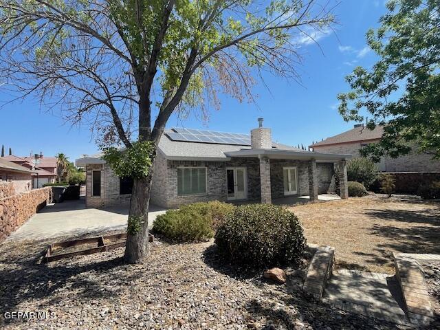 rear view of property featuring solar panels and a patio area