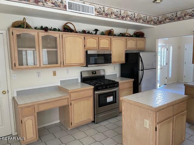 kitchen featuring tile counters, stainless steel appliances, and light brown cabinets