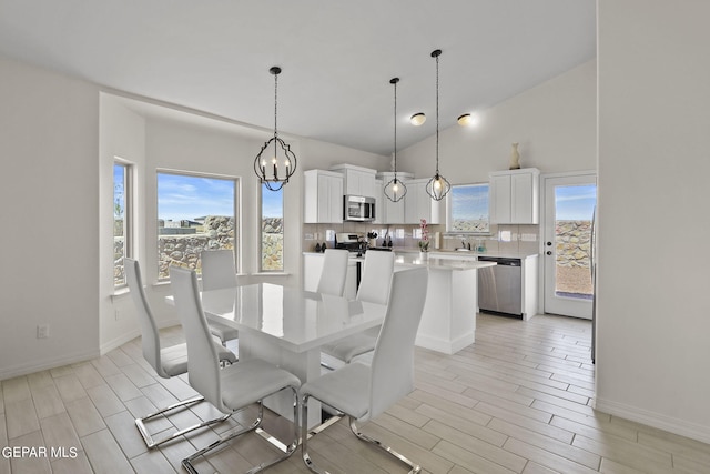 dining area with a chandelier, a towering ceiling, and light hardwood / wood-style flooring