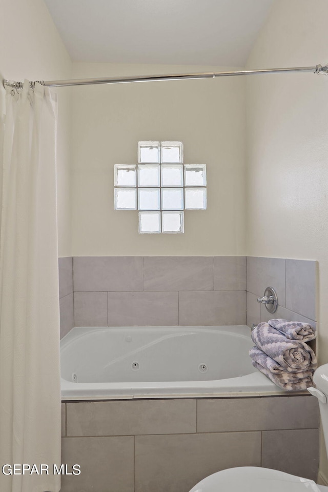 bathroom featuring toilet, tiled tub, and vaulted ceiling