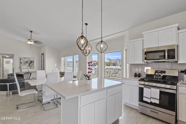 265 Adamtowne Dr, El Paso, TX 79928 - kitchen with appliances with stainless steel finishes, light countertops, a center island, backsplash, and light wood-type flooring