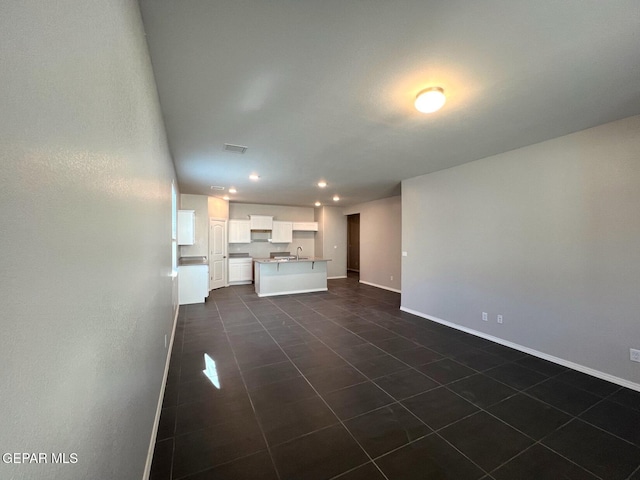 unfurnished living room featuring dark tile patterned flooring and sink