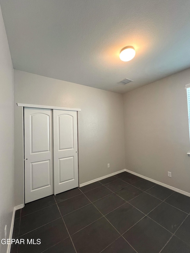 unfurnished room with a textured ceiling and dark tile patterned floors