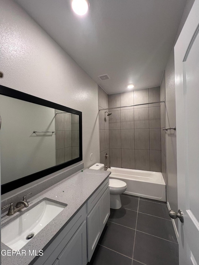 full bathroom with tile patterned flooring, vanity, tiled shower / bath combo, and toilet