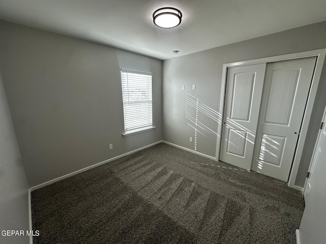 unfurnished bedroom featuring a closet and dark colored carpet