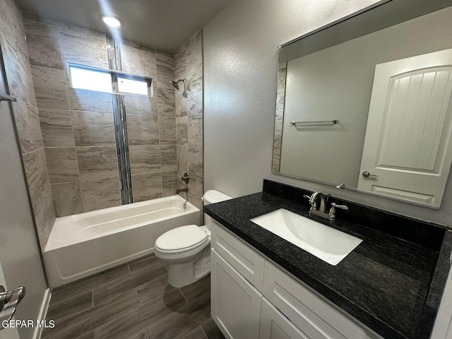 full bathroom featuring tiled shower / bath, hardwood / wood-style flooring, vanity, and toilet