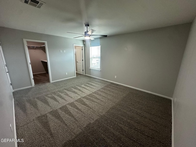 unfurnished bedroom featuring ceiling fan, a closet, carpet, and a walk in closet