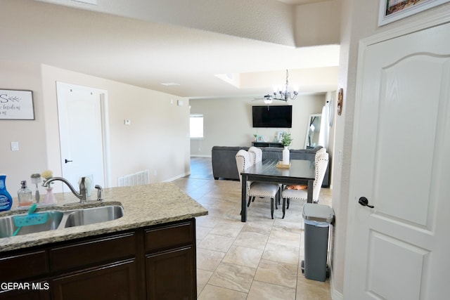 kitchen with dark brown cabinets, sink, hanging light fixtures, and an inviting chandelier