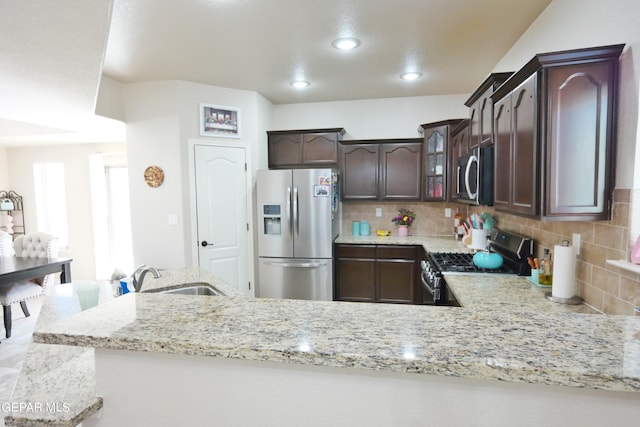 kitchen featuring sink, tasteful backsplash, kitchen peninsula, dark brown cabinets, and appliances with stainless steel finishes