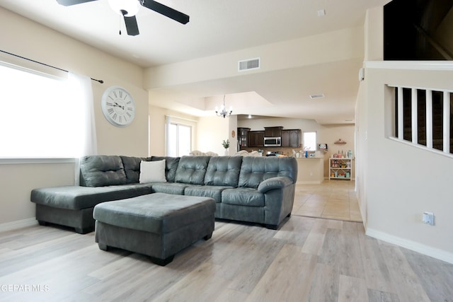 living room featuring ceiling fan with notable chandelier and light wood-type flooring