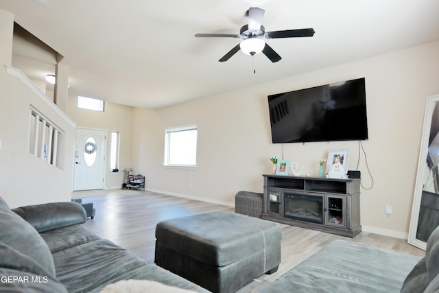 living room with ceiling fan, a fireplace, and light hardwood / wood-style floors