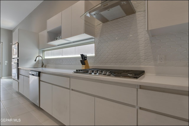 kitchen featuring exhaust hood, white cabinets, sink, appliances with stainless steel finishes, and tasteful backsplash