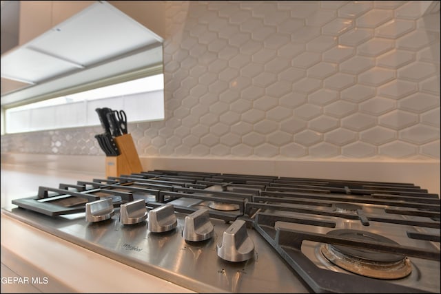 details featuring backsplash and stainless steel gas stovetop