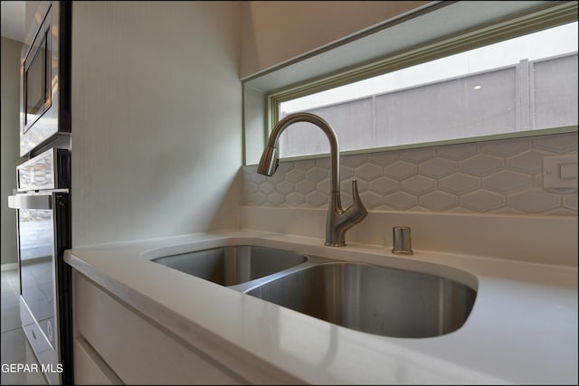 details featuring backsplash, sink, and stainless steel appliances