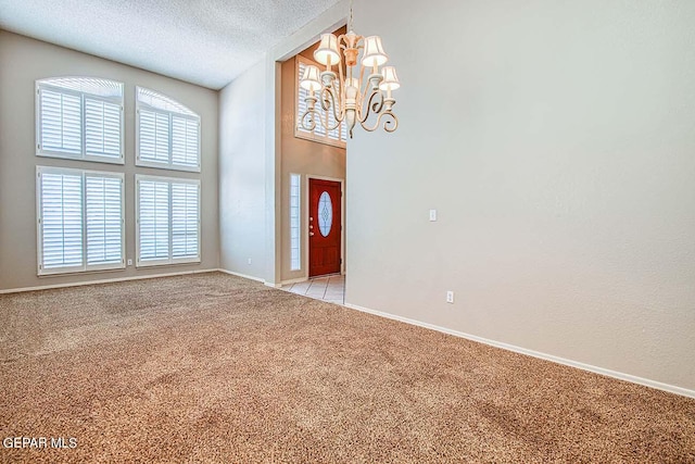 spare room with a chandelier, a textured ceiling, and light colored carpet