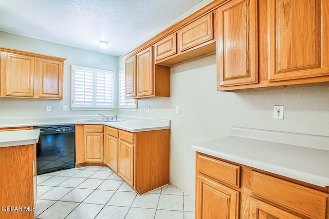 kitchen with sink, dishwasher, light tile floors, and a textured ceiling