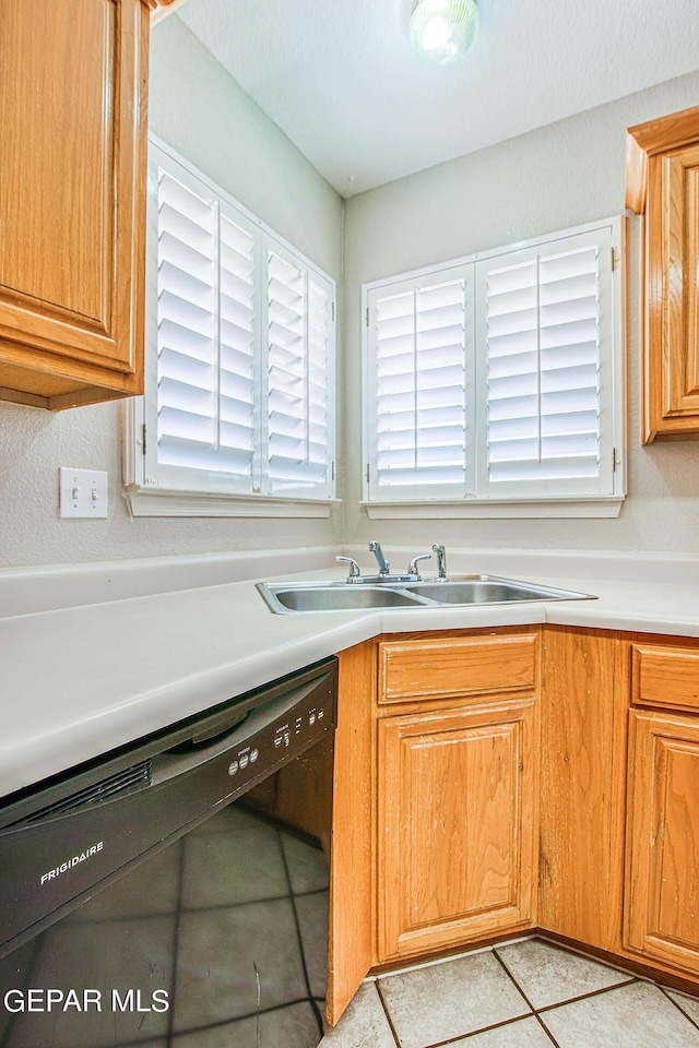 kitchen featuring black dishwasher, sink, and light tile floors