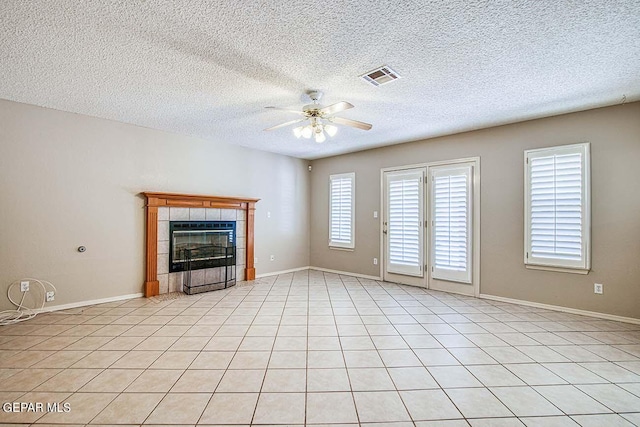 unfurnished living room with ceiling fan, a tile fireplace, a textured ceiling, and light tile floors