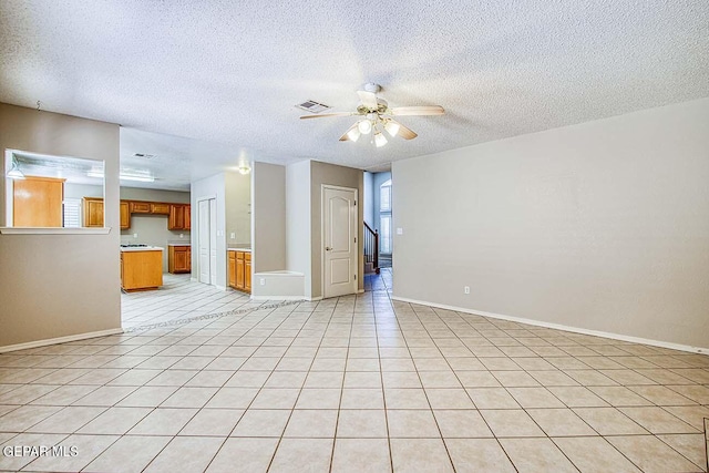 unfurnished living room with ceiling fan, a textured ceiling, and light tile floors