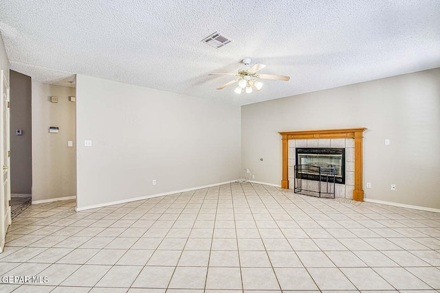 unfurnished living room with light tile flooring, a textured ceiling, a tile fireplace, and ceiling fan