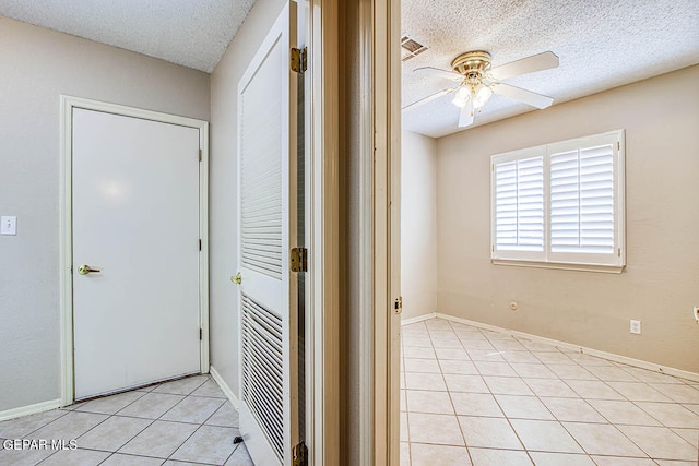 corridor with a textured ceiling and light tile floors